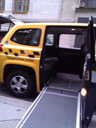 photo of a ramp extended outside of a yellow Nissan MV-1