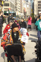 photo of demonstrators, most of whom in wheelchairs, heading to Taxi of Tomorrow site