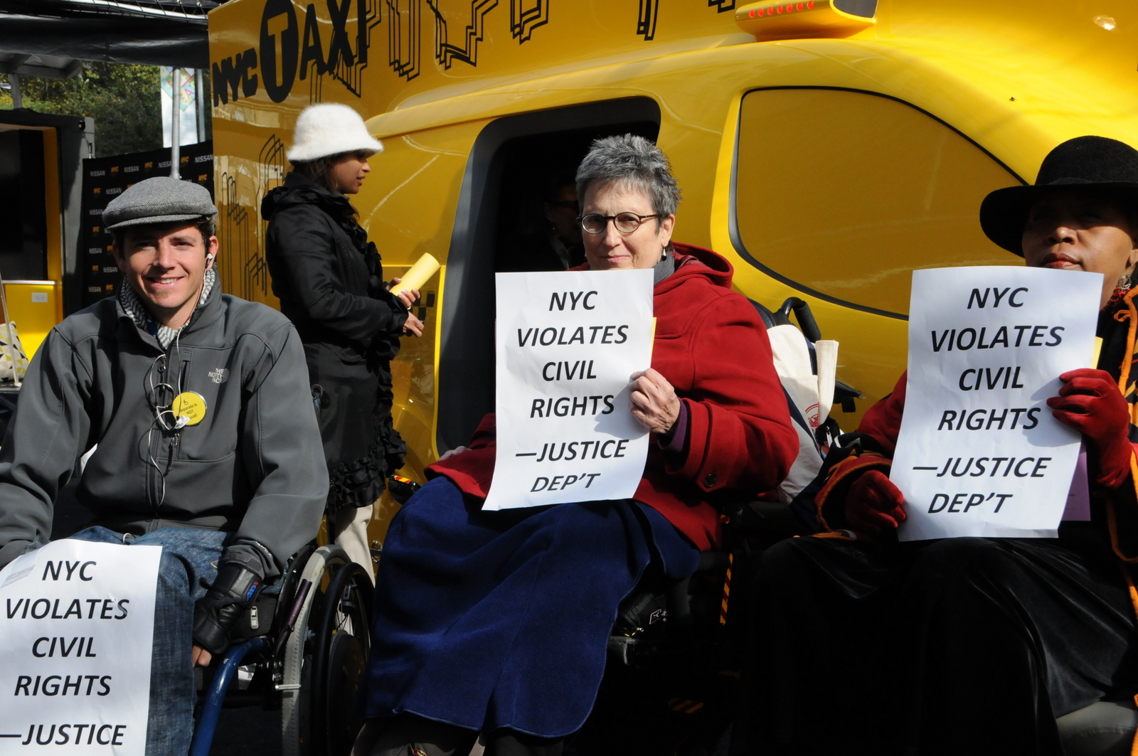 photo of group holding signs reading New York City Violates Civil Rights - Justice Department