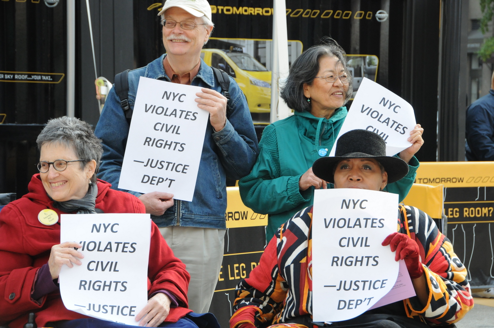 photo of four of the demonstrators holding signs with a Justice Department quote, New York City Violates Civil Rights