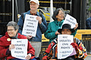 photo of four of the demonstrators holding signs stating a Justice Department quote, New York City Violates Civil Rights