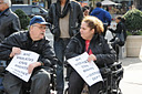 photo of two of the demonstrators, in wheelchairs, chatting with each other