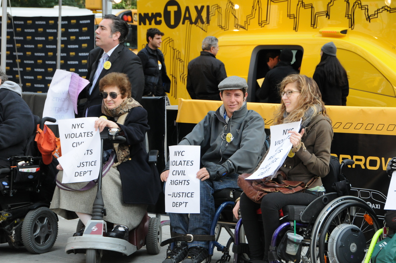 photo of some demonstrators, mostly in wheelchairs, in front of Taxi of Tomorrow