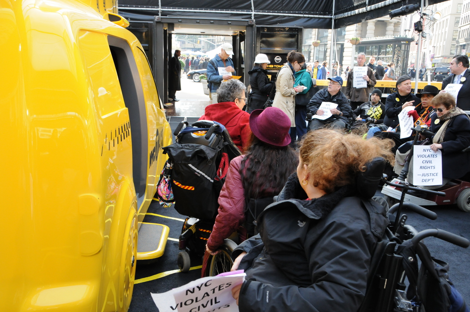 photo of demonstrators in wheelchairs unable to get into the inaccessible Taxi of Tomorrow